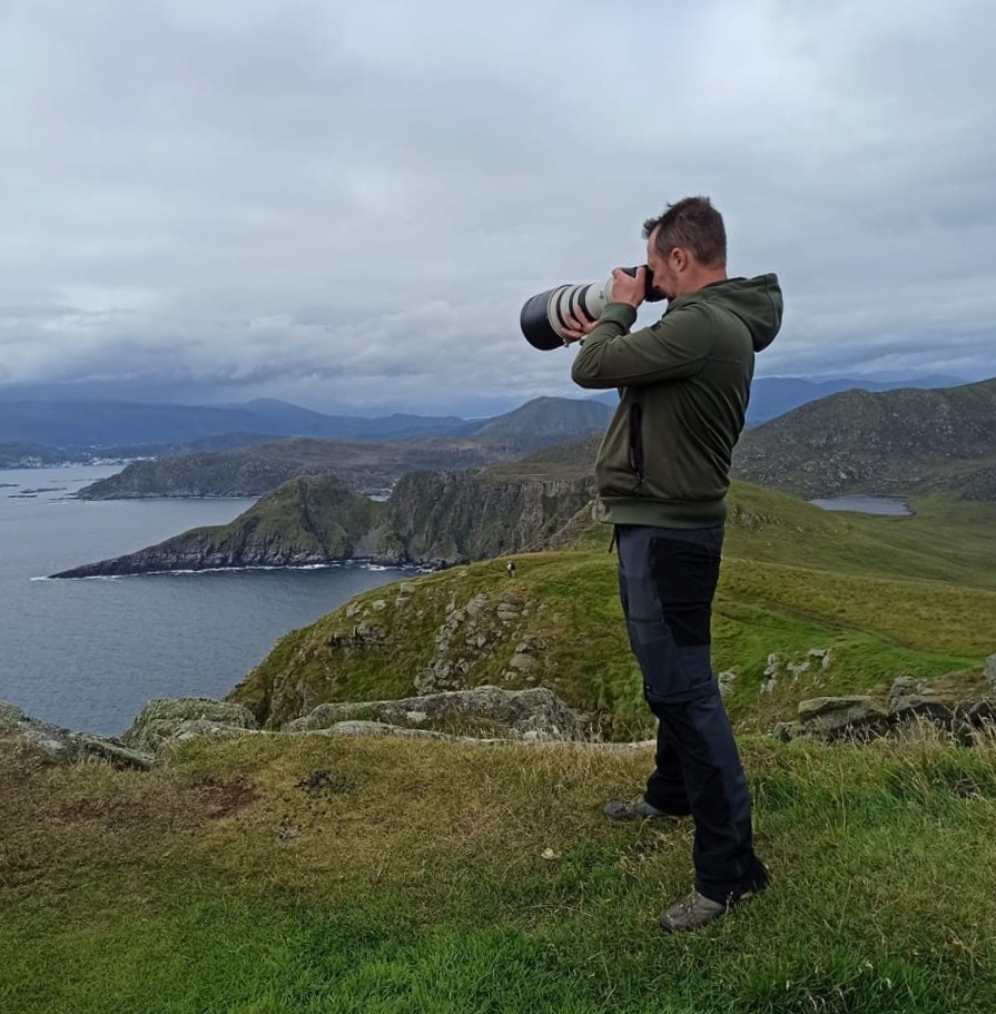 Sidney Deblauwe staat te fotograferen aan de klifrand op het vogeleiland Runde in Noorwegen.